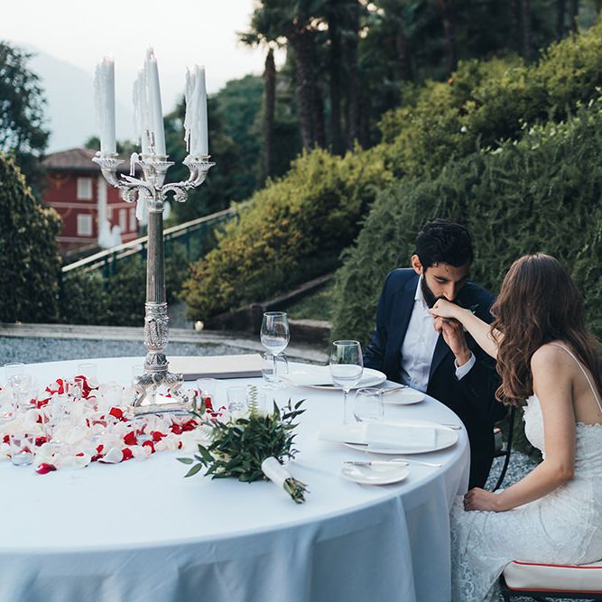 Groom in Taliare Navy Suit Kissing His Brides Hand at Their intimate Wedding Reception