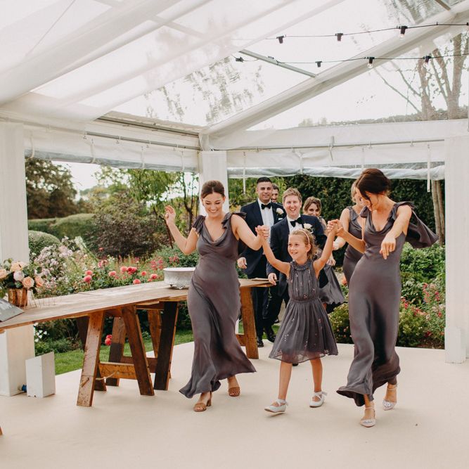Bridal Party Entrance | Flowers from Topiary Tree | Bride in Karen Willis Holmes | Groom in Custom Made Suit by Suit Supply | Summer Wedding at Family Home in Kent | Glass Marquee from Academy Marquees | Frances Sales Photography