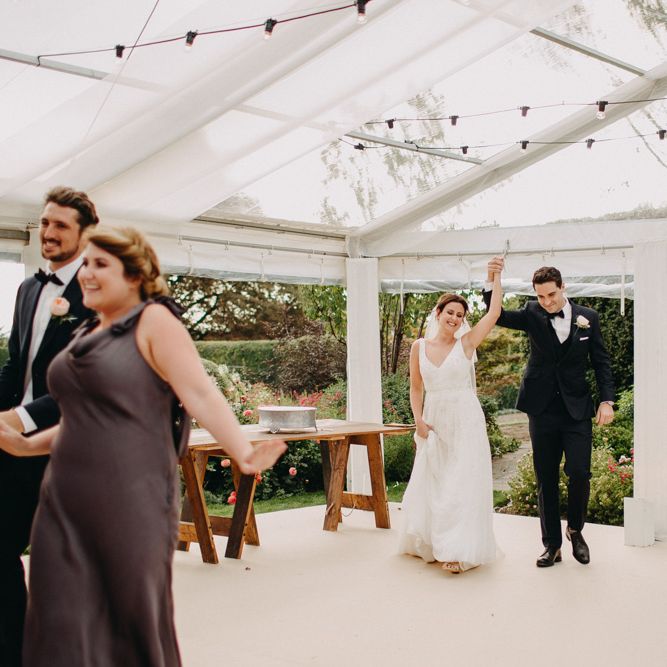 Bridal Party Entrance | Flowers from Topiary Tree | Bride in Karen Willis Holmes | Groom in Custom Made Suit by Suit Supply | Summer Wedding at Family Home in Kent | Glass Marquee from Academy Marquees | Frances Sales Photography