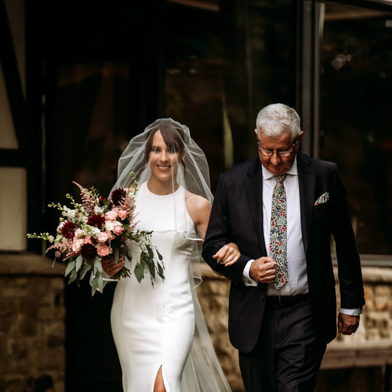 Bride walking down the aisle in fitted halter neck wedding dress
