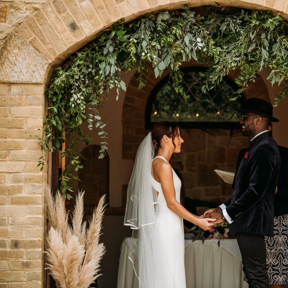 Outdoor wedding ceremony at The Ravenswood with bride and groom holding hands