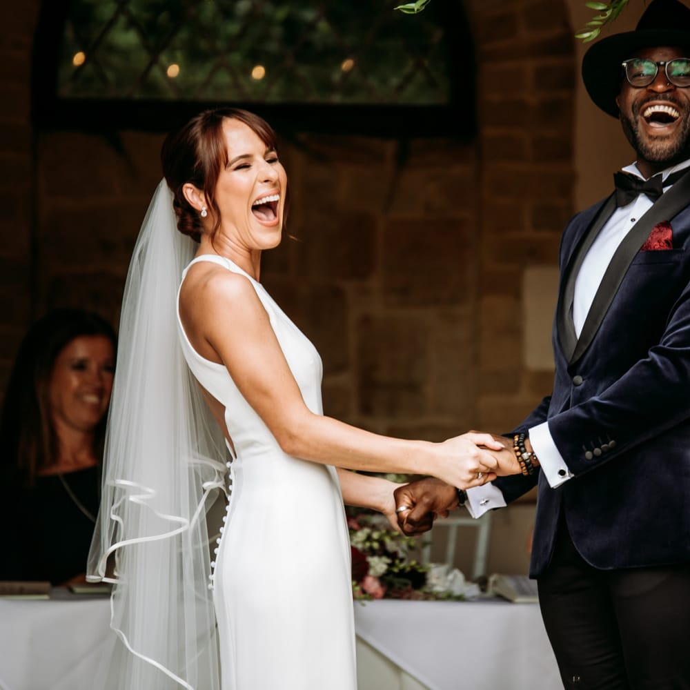 Bride and groom holding hands laughing at The Ravenswood wedding ceremony