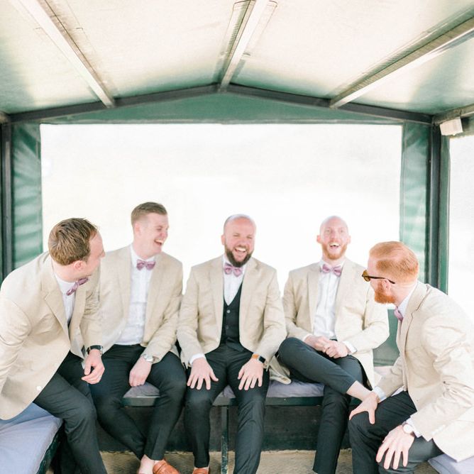 Groomsmen in Beige Jackets and Bow Ties on the Back of a Tractor