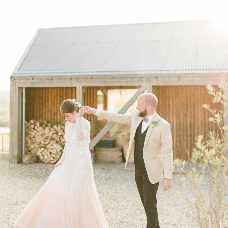 Groom in Beige Blazer and Pink Bow Tie Twirling His Bride in a Needle &amp; Thread Pink Ombre Wedding Dress