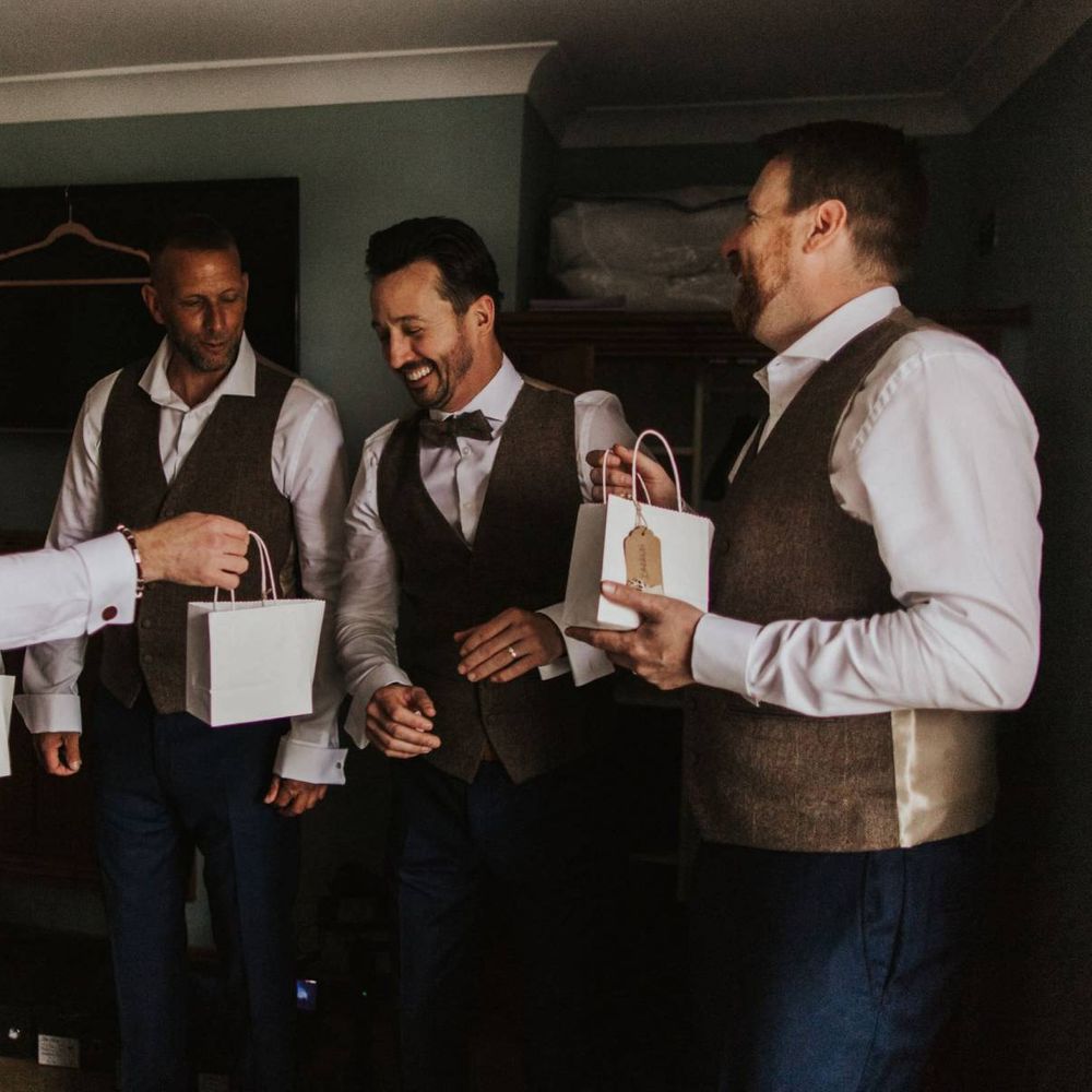 Groom and his groomsmen wearing brown waistcoats with blue suit trousers