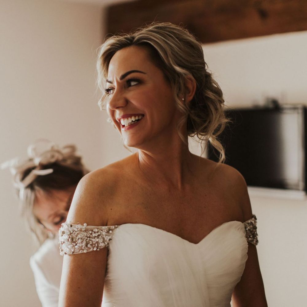 Bride wearing off  the shoulder embellished dress with sweetheart neckline and updo hairstyle