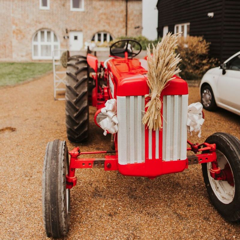 Vintage red tractor transport for outdoor summer wedding at The Ferry House Inn