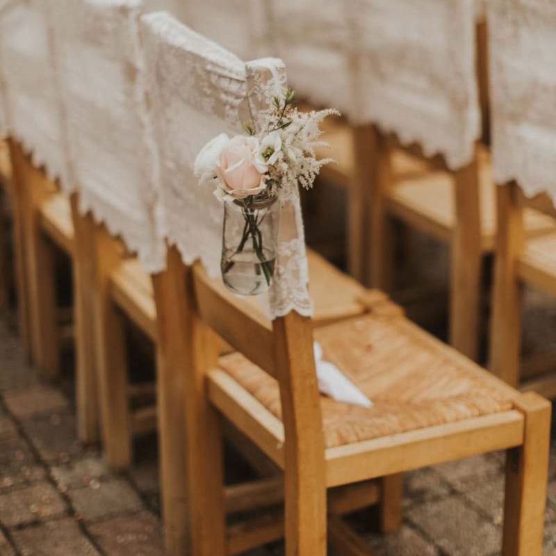 Lace chair covers and delicate pink rose decor for outdoor summer ceremony with rustic styling