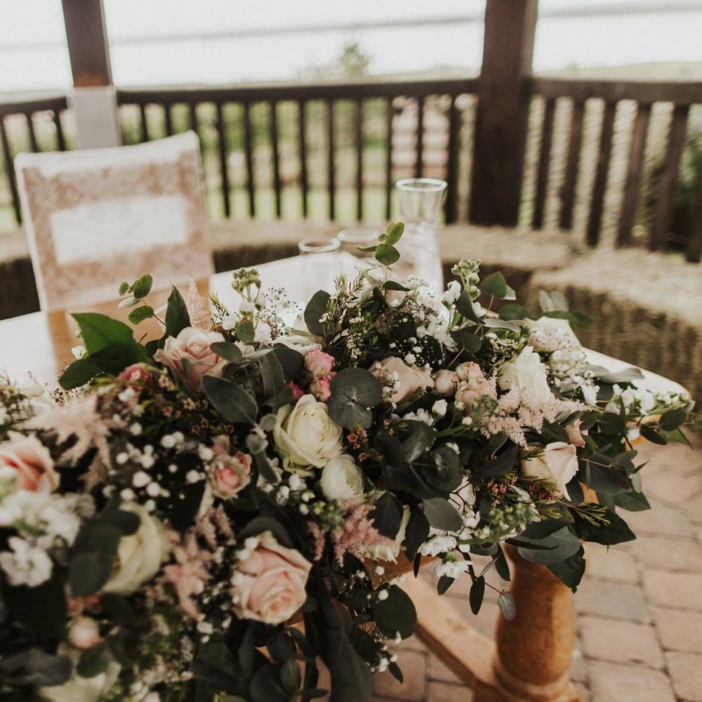 Pink rose floral decor and lace chair covers at The Ferry House Inn for an outdoor rustic ceremony