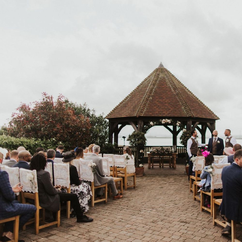 Outdoor summer ceremony at The Ferry House Inn with lace chair covers and pink rose flower decor