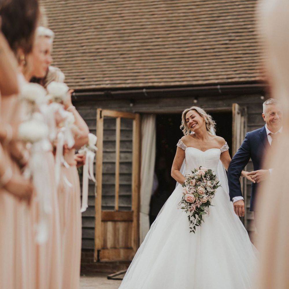 Bride wearing embellished off the shoulder sweetheart neckline dress and pink rose bouquet at The Ferry House Inn outdoor ceremony