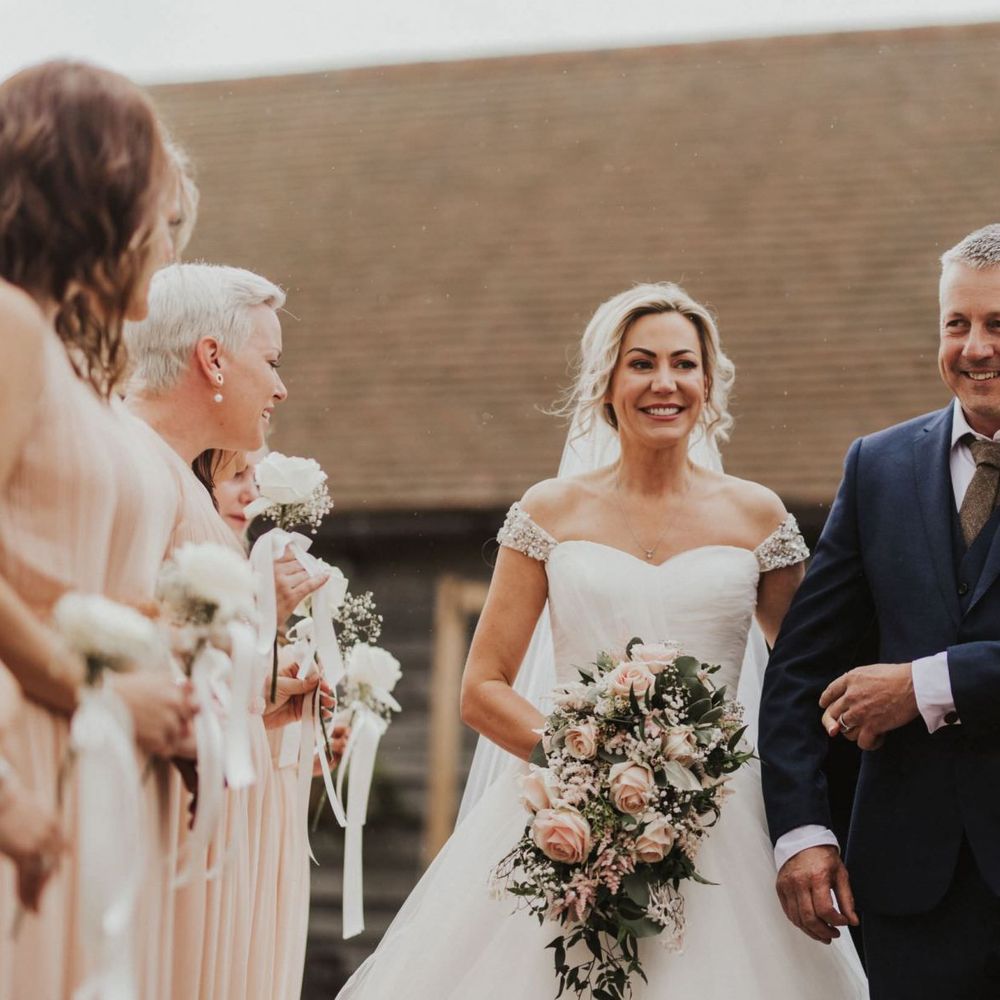 Bride wearing embellished off the shoulder sweetheart neckline dress and pink rose bouquet at The Ferry House Inn outdoor ceremony