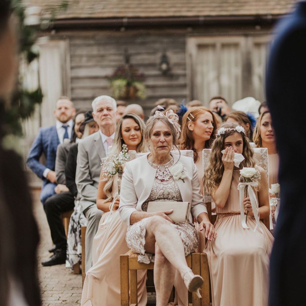 Guests at outdoor ceremony with nude bridemaid dresses and rose bouquets