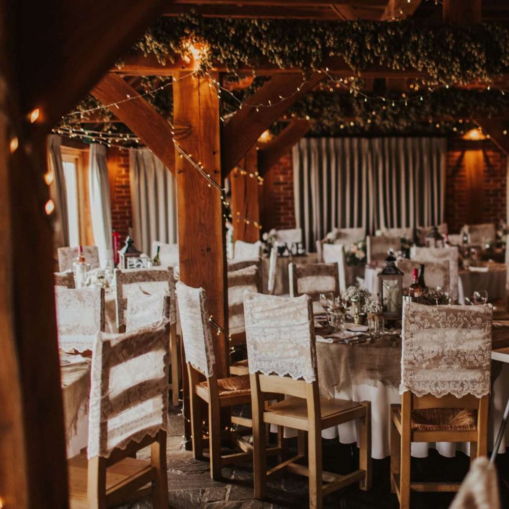 Rustic wedding reception with lace chair covers and fairy lights at The Ferry House Inn