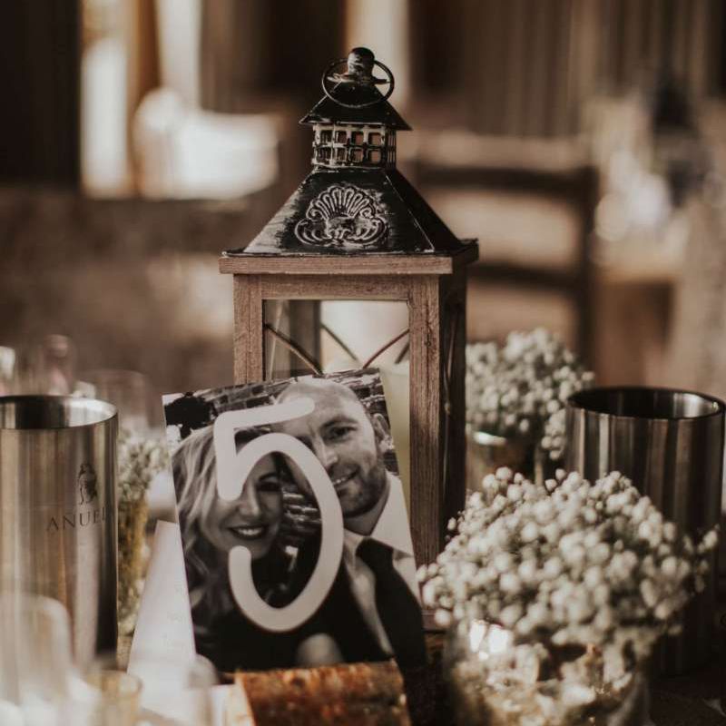 Rustic styling with photograph table numbers and lantern decor at The Ferry House Inn