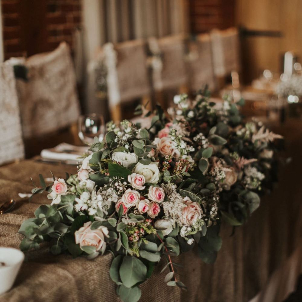 Pink rose floral decor at summer wedding with rustic styling and lace chair covers