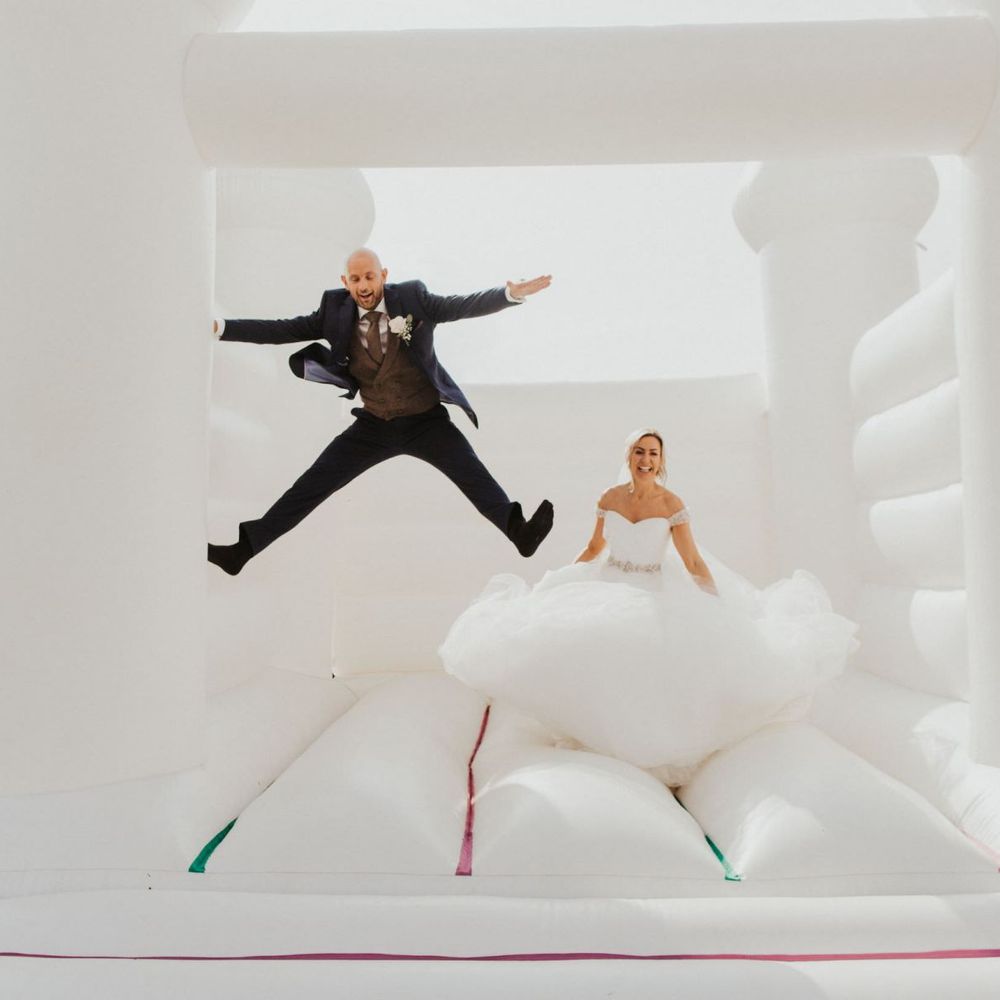 Bride and groom at outdoor celebration with white bouncy castle
