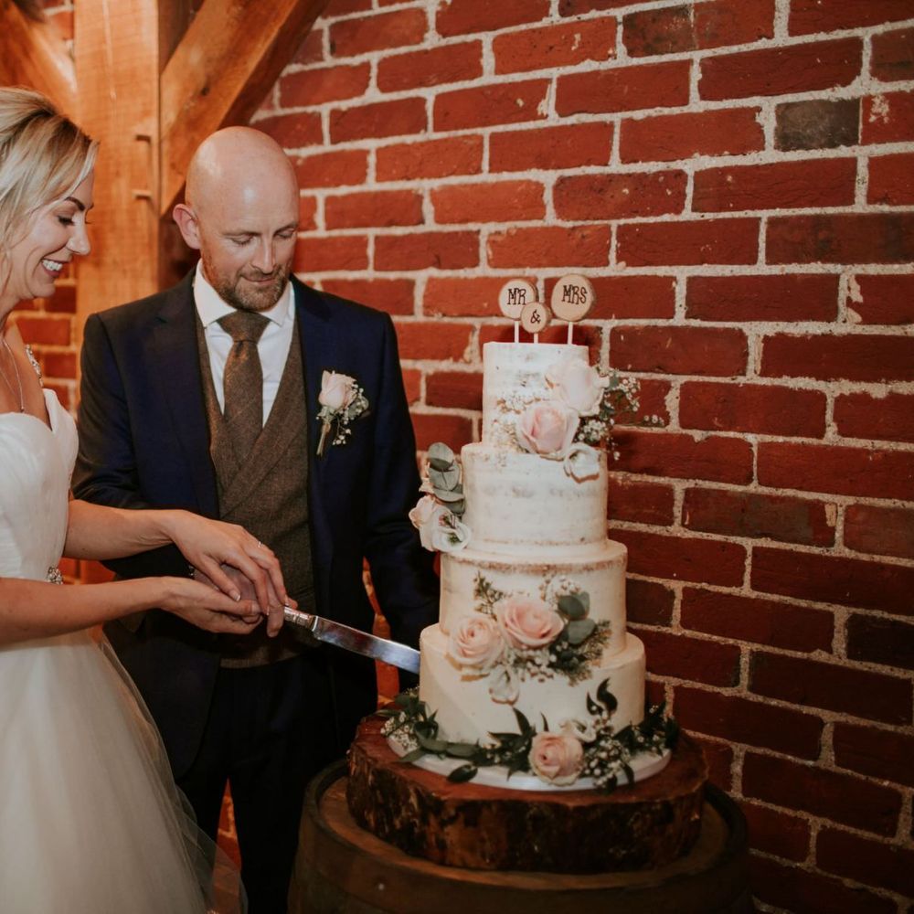 Bride and groom cut the semi naked wedding cake at Bride and groom at The Ferry House Inn