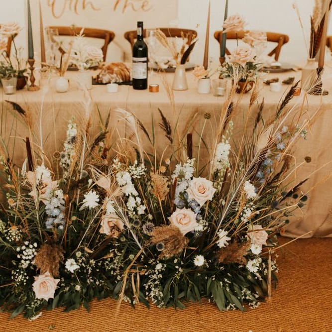 Pink and blue flowers with dried grasses and foliage for August 2020 wedding reception