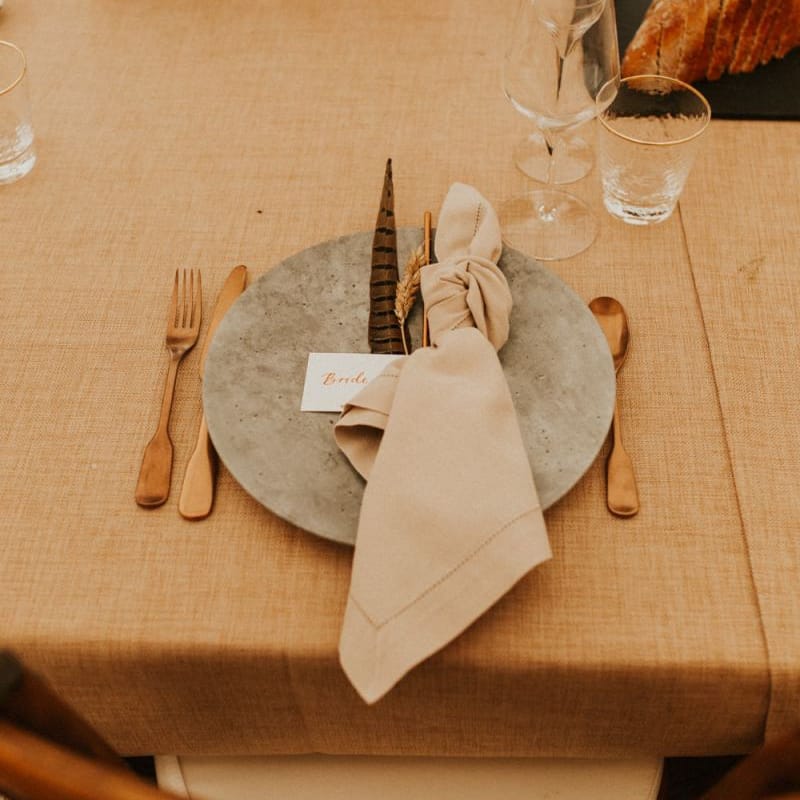 Boho place setting with concrete plate, gold cutlery and linen napkin