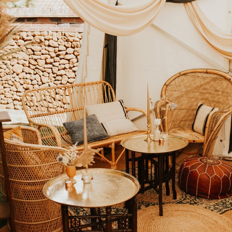 Boho seating corner with peacock chairs, pouffes and mats