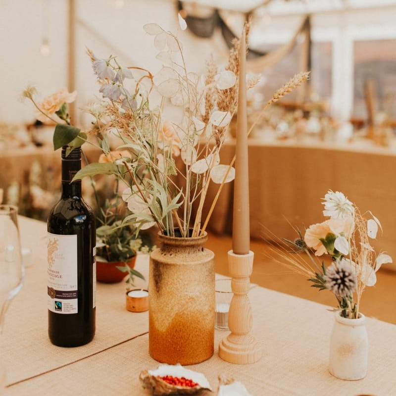 Flower stems and dried grasses in ink wells for bohemian August 2020 wedding reception