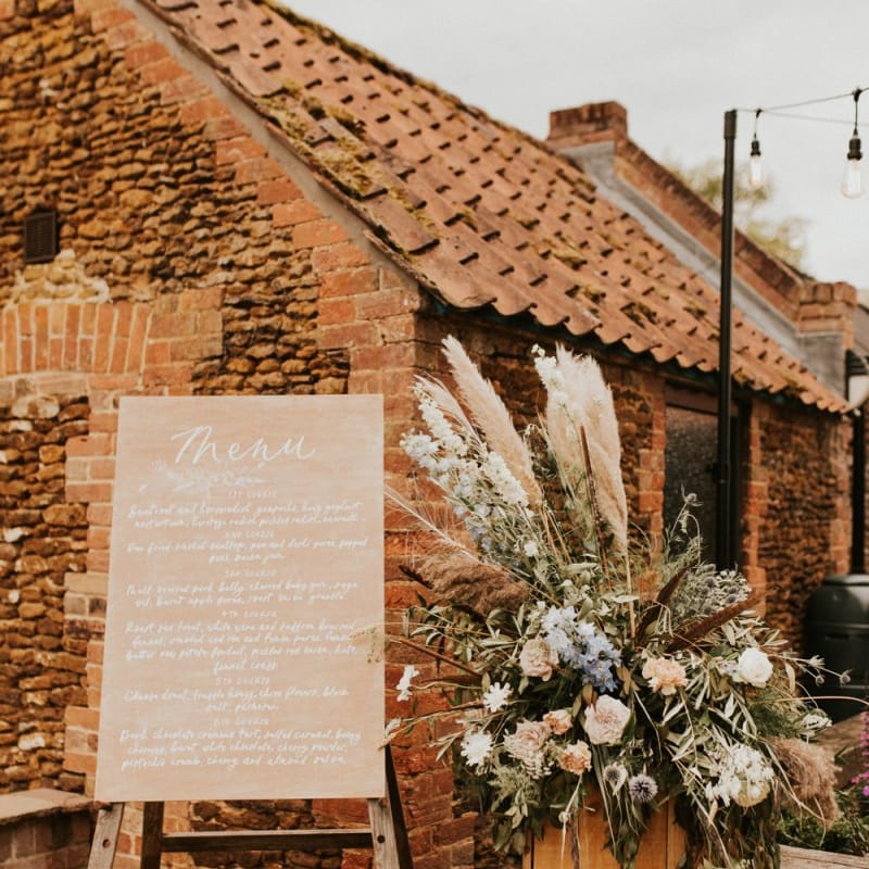Wooden menu sign and floral arrangement at August 2002 wedding