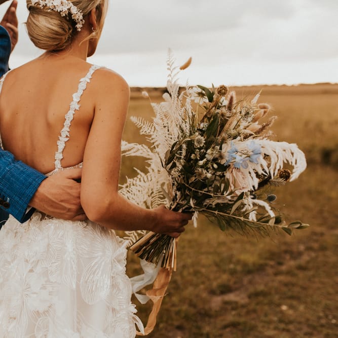 Groom in blue blazer embracing his bride in a Galia Lahav wedding