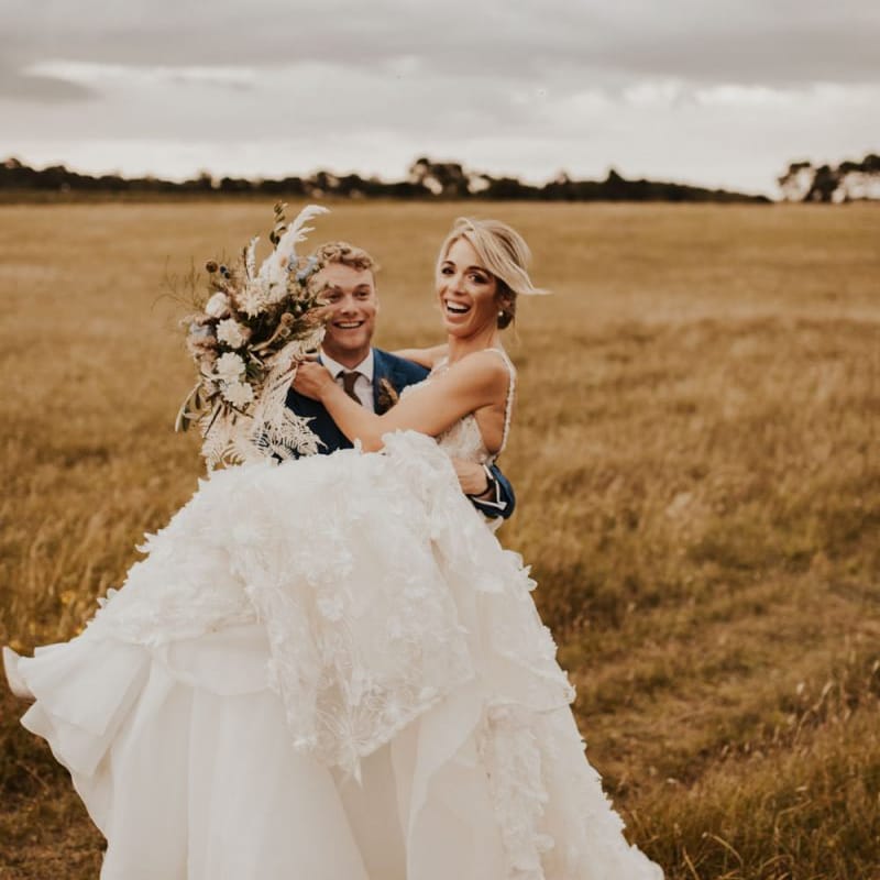 Groom picking up his bride in a lace Galia Lahav wedding dress