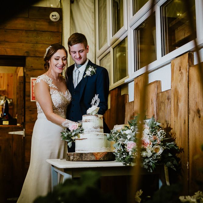 Cutting the Semi Naked Wedding Cake | Bride in Lace Long Sleeve Martina Liana Wedding Dress | Groom in Navy Three-piece Suit | Lusty Glaze Beach Wedding Newquay Cornwall | Alexa Poppe PhotographyLusty Glaze Beach Wedding Newquay Cornwall | Alexa Poppe Photography