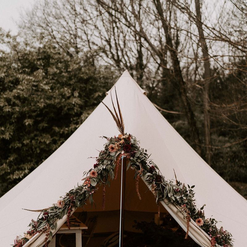 Bell Tent with Flower Covered Entrance and Cosy Seating Area Inside