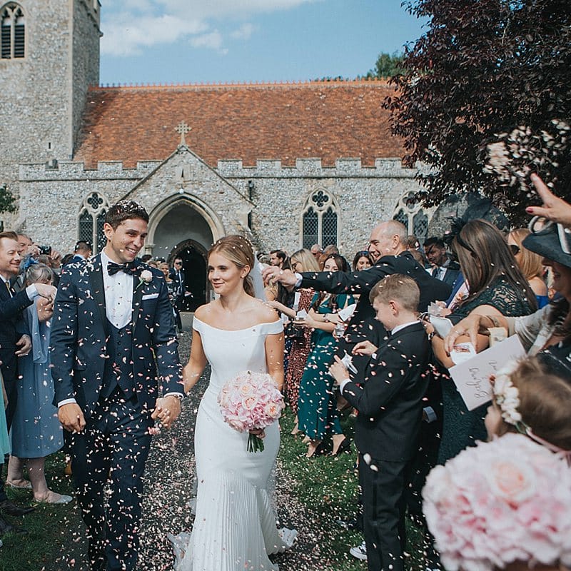 Church Confetti Moment | Bride in Suzanne Neville Bardot Nouveau Wedding Dress | Groom in Black Tie | Pastel Pink &amp; Mint Green Wedding at Granary Estates Suffolk | Julia &amp; You Photography