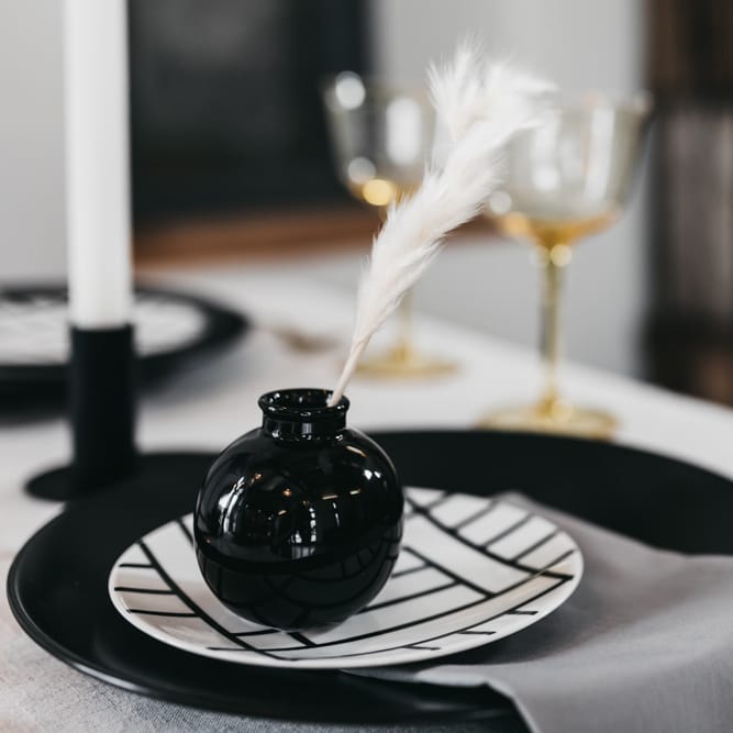 Place setting with monochrome tableware and white feather decor