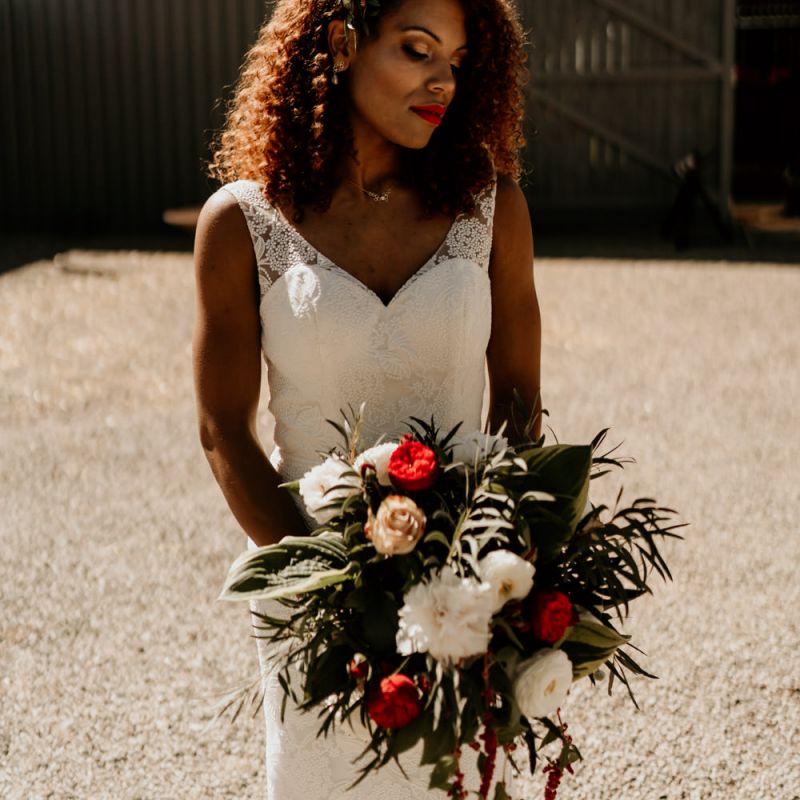 Black Bride with Afro Hair in Lace Wedding Dress Holding a Red and White Wedding Bouquet