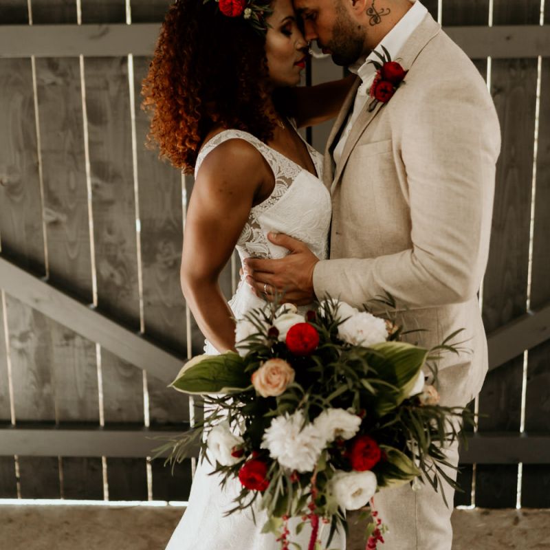 Black Bride with Afro Hair in a Lace Wedding Dress and Groom in Blazer Embracing Under a neon Wedding Sign