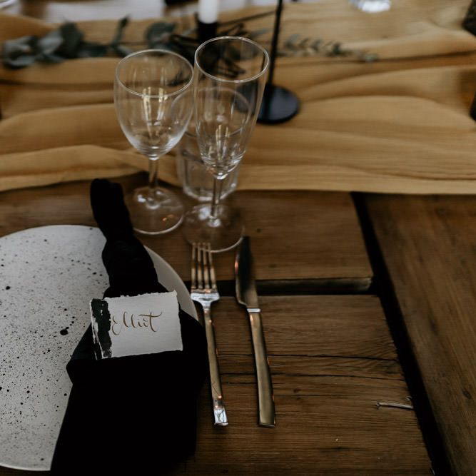 Elegant Place Setting with Speckled Tableware, Black Table Linen and Calligraphy Name Place Card