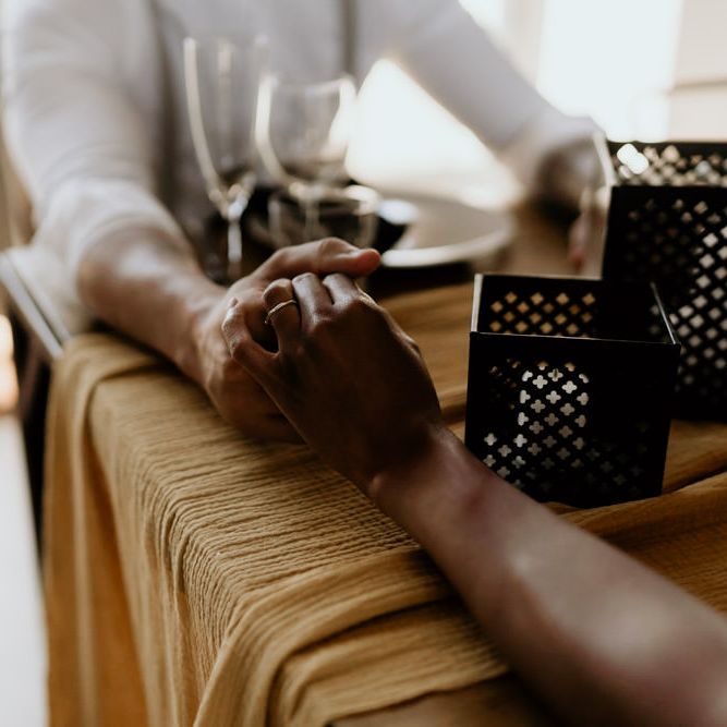 Black Bride and Groom Holding Hands Across The Table