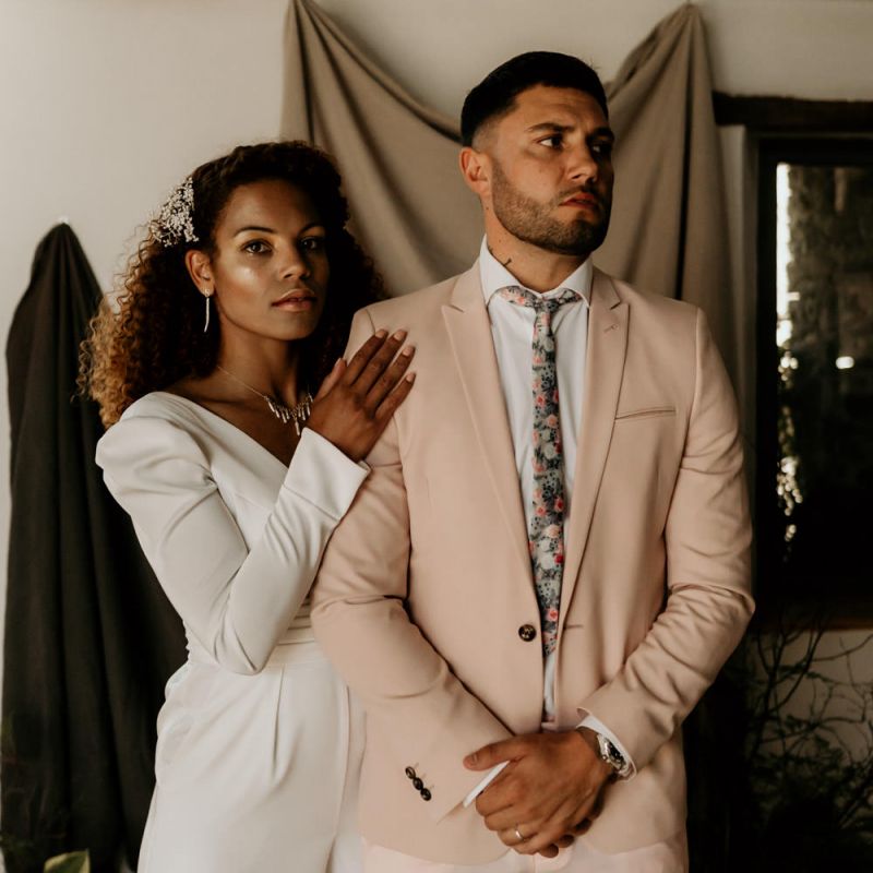 Black Bride with Afro Hair  in White Jumpsuit with Groom in Pink Blazer and Floral Tie