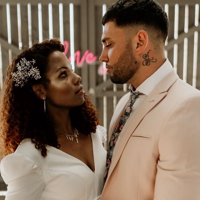 Black Bride with Afro Hair and Cheek Highlighter and Groom in Pink Blazer and Floral Tie