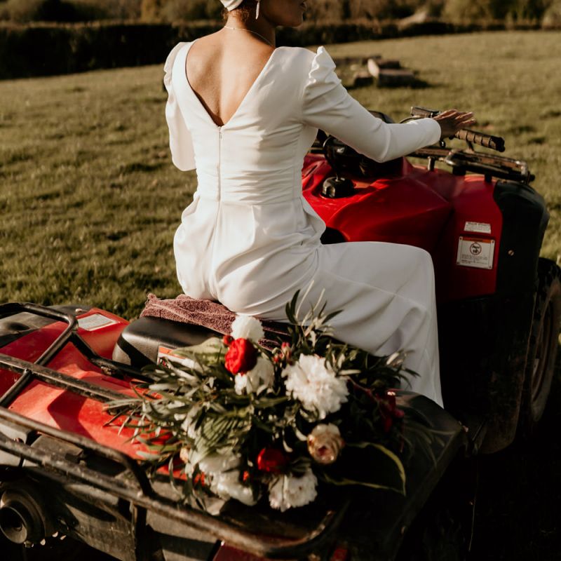 Black Bride in White Jumpsuit and Head Wrap Sitting Quad Bike