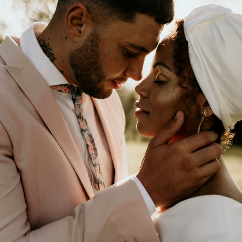 Black Bride with Head Wrap and Cheek highlighter and Groom in Pink Blazer Embracing