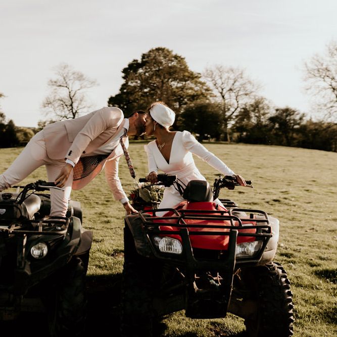 Black Bride in White Jumpsuit with Head Wrap  and Groom in Pink Suit on Quad Bikes