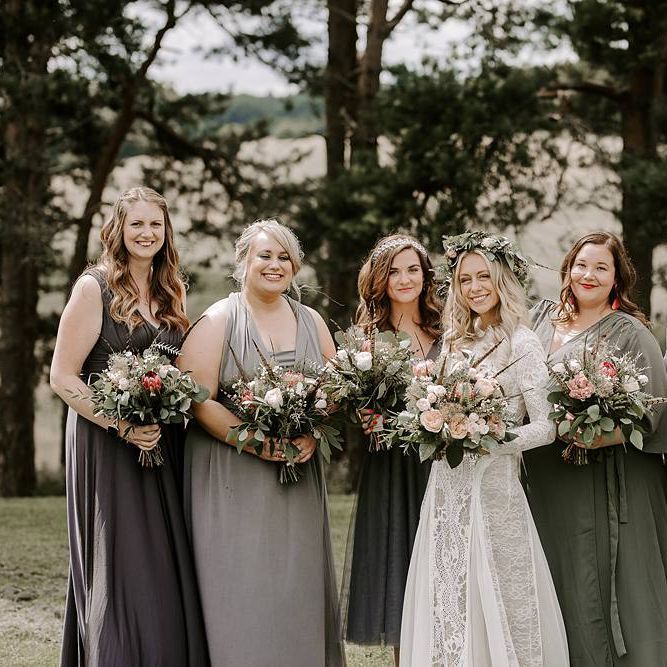 Bridesmaids in grey dresses clutch Protea bouquet