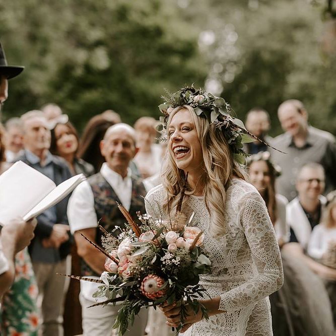 Bride laughs during ceremony holding a Protea bouquet