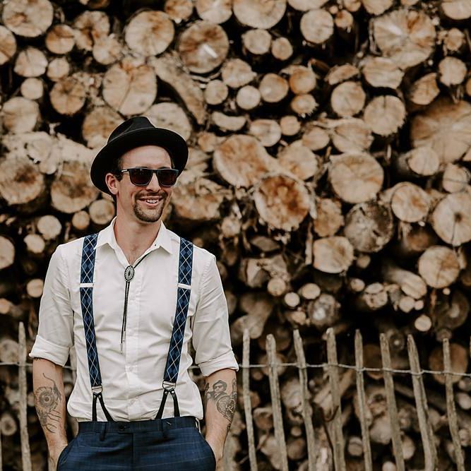 Groom in braces and a hat for boho wedding