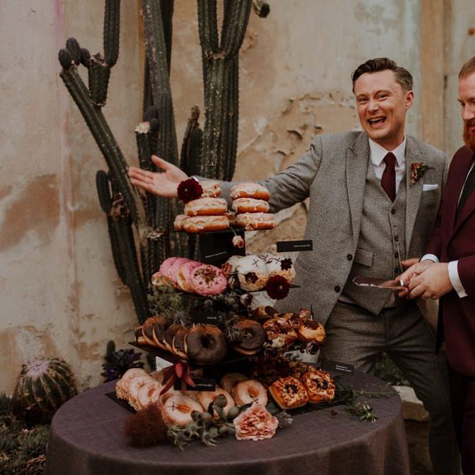Groom and groom cutting the doughnut tower wedding cake