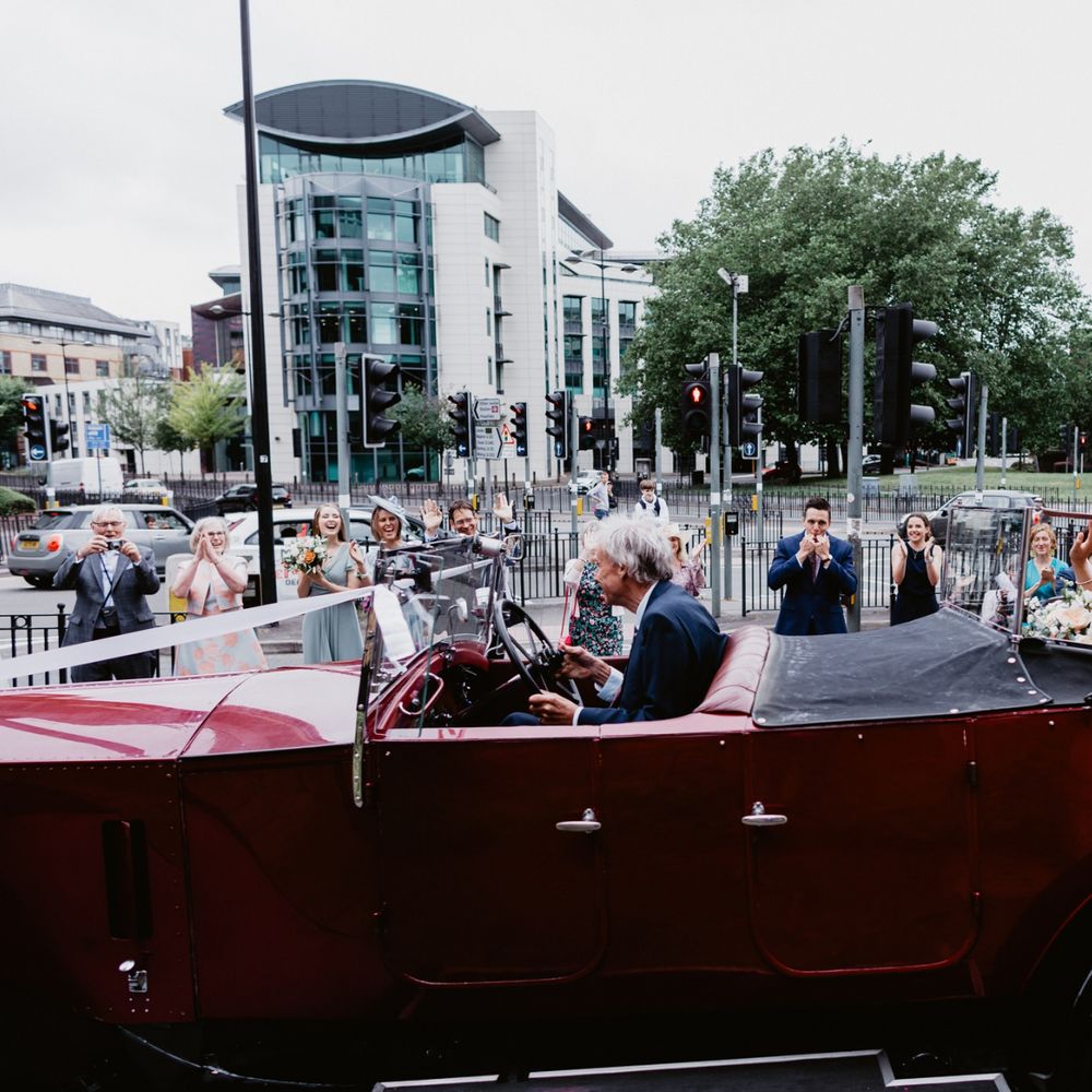 Bride and groom driving off in vintage wedding car