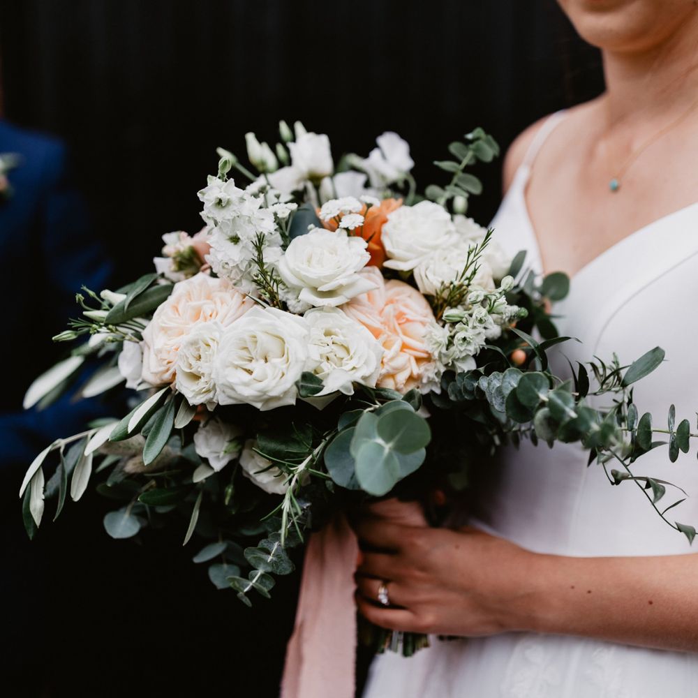 peach and white rose wedding bouquet tied with foliage and ribbon