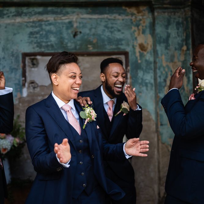 Bride in Navy Three Piece Suit and Pink Tie Surrounded by Her Wedding Party