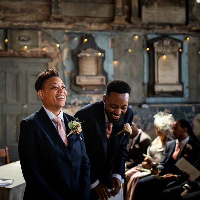 Bride in Navy Suit and Pink Tie Standing at The Asylum Altar Laughing with her Best Man